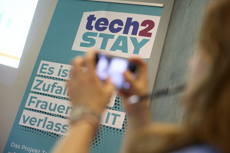 Eine Frau macht ein Foto von einem Tech2stay-Aufsteller