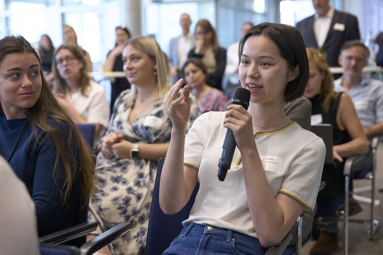 Junge Frau im Publikum spricht in ein Mikrofon